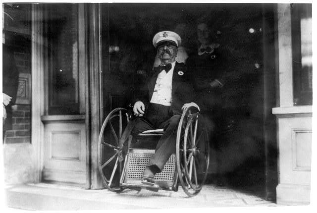Maj. General Daniel E. Sickles in wheelchair; coming out of building